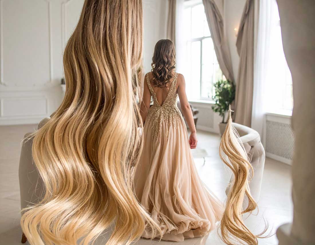 Frau mit langen, gewellten Echthaar-Bonding-Extensions in einem champagnerfarbenen Abendkleid – perfekte Haarverlängerung für glamouröse Anlässe