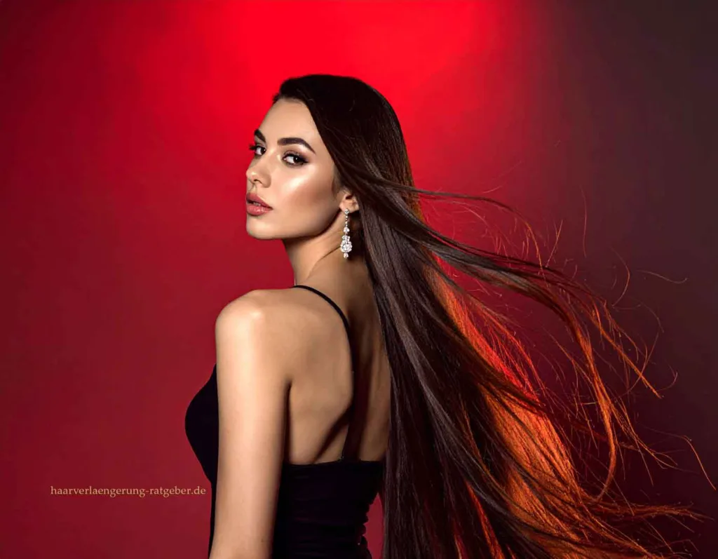 Frau mit langen, glänzenden Haaren und eleganten Bonding Extensions vor rotem Hintergrund – Symbol für Selbstbewusstsein und innere Stärke.